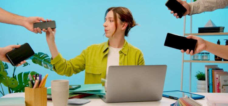 person sitting at a desk while multiple device handed to her