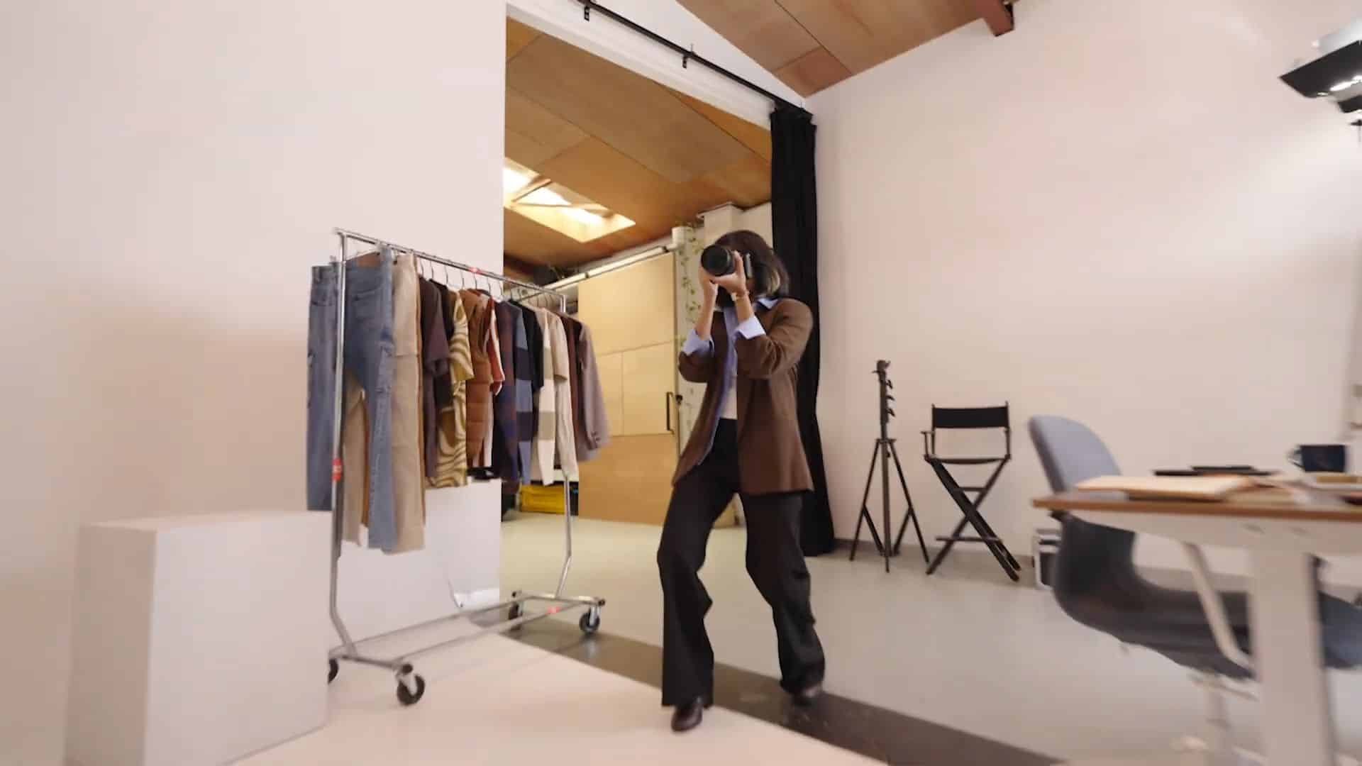 Photographer in studio taking pictures near clothing rack