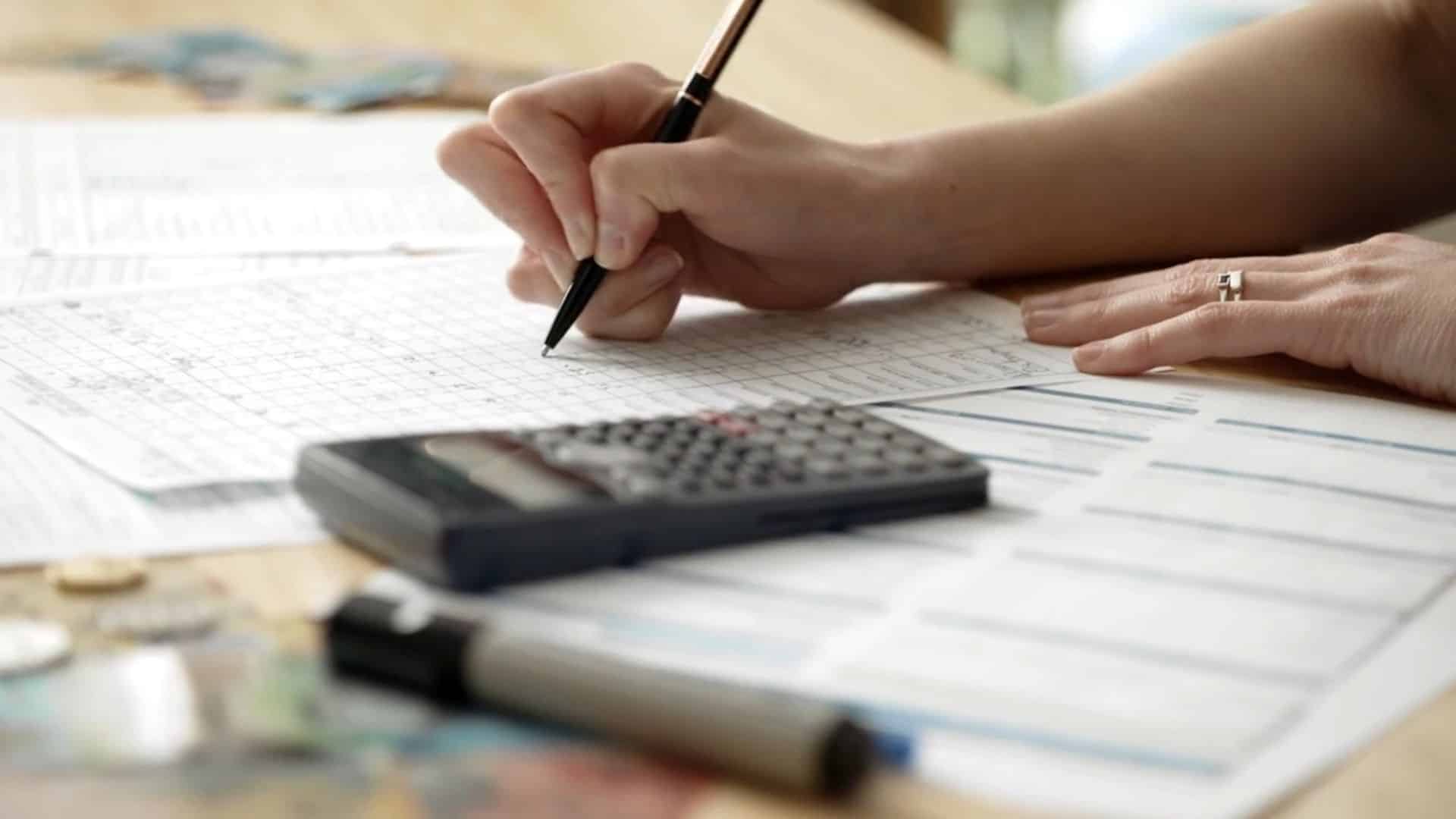 close-up of someone’s hand writing on a financial spreadsheet