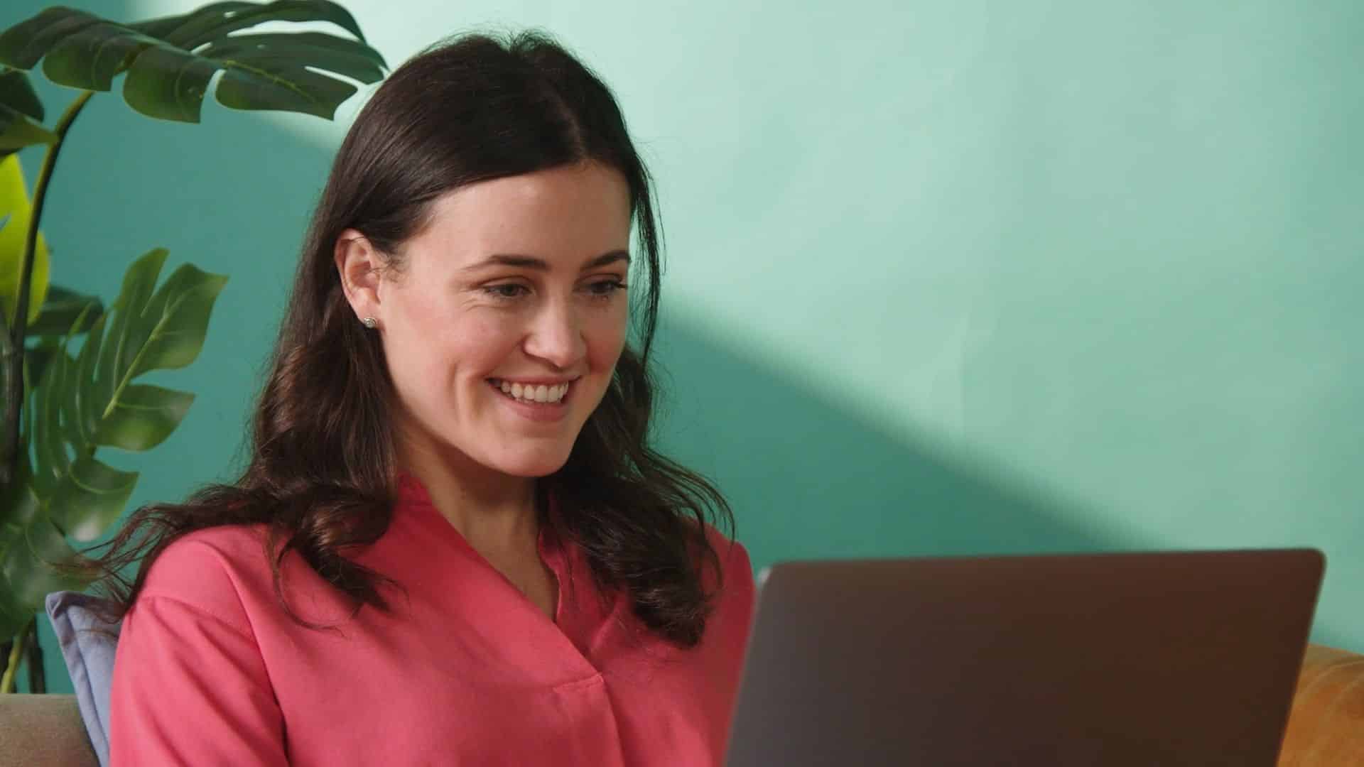 woman smiling while working on a laptop